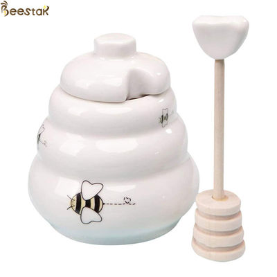ふたが付いている陶磁器の蜂蜜の鍋そしてスプーンの陶磁器の白い蜂蜜の鍋